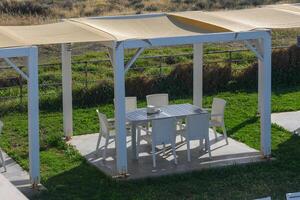 Outdoor dining area with shaded pergola invites relaxation and enjoyment in a tranquil coastal setting photo