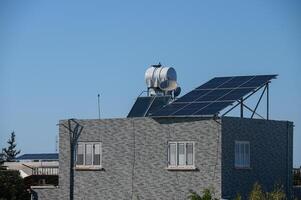 Innovative rooftop design showcasing solar panels and a water heater under clear blue skies photo