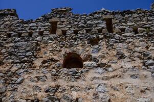Stone-framed window inside the castle offering mountain views. Historical atmosphere and old architecture. photo