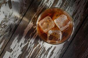 Refreshing drink with ice cubes on rustic wooden table during a warm evening photo