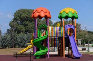 Brightly colored playground structure invites play and imagination in a sunny park setting during the afternoon hours, surrounded by nature's greenery photo
