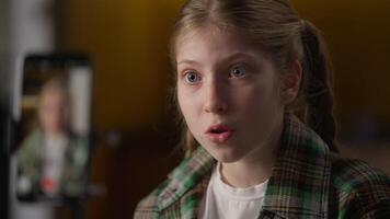 Disappointed little girl blogger influencer record mobile phone blog complaining Caucasian child kid vlogger influence talking opinion unhappy discussing on smartphone camera tripod gesturing at home video