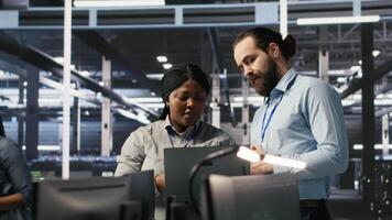 Data center engineering team colleagues collaborating on blade servers maintenance to ensure continuous AI processing. Technicians manage infrastructure supporting machine learning pipelines, camera A video