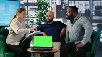 Business people negotiate to align on vision next to mockup display on laptop, using data driven insights and cultural diversity to support leadership and corporate success. Camera B. video
