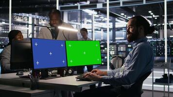 Data center admin using isolated screen mockup PC to update storage arrays software, configuring network virtualization. Server room IT expert using chroma key computer to verify settings, camera A video