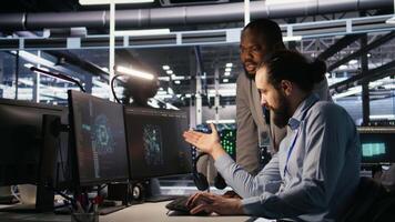 Supervisor in server room monitoring worker managing AI training datasets. African american team leader and engineer in data center supervising system operations supporting neural networks, camera A video