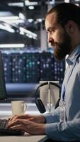 Vertical Server farm worker trying to fix hacked equipment systems and protect equipment. Data center engineer reacting to virus popup warning on computer screen, launching emergency response protocol video
