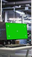 Vertical Green screen desktop PC set up in data center overseeing server infrastructure powering artificial intelligence workflows. Chroma key displays used for monitoring backend systems video