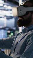 Vertical Data center technician using VR headset to monitor neural network AI LLM visualization. Server room worker using virtual reality tech to oversee rigs powering machine learning processes, camera A video