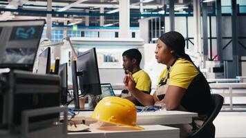 African american engineer analyzes energy consumption software in solar factory, uses PC program to enhance solar cell production and reduce faults in automated machinery systems. Camera B. video