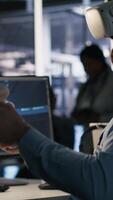 Vertical Data center employee wearing VR headset using artificial intelligence neural networks technology. Server farm programmer using AI programming language and virtual reality to update hardware, camera A video