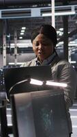 Vertical Data center system administrator pleased by neural network outputs after completing software updates. IT expert smiling, looking at laptop screen, optimizing configuration server hub rigs, camera A video