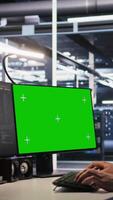 Vertical Data center technician doing software updates using green screen mockup computer. Server room IT specialist , optimizing infrastructure using chroma key isolated screen PC, camera A video