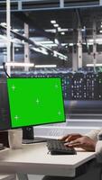 Vertical Data center programmer coding on green screen PC, monitoring AI systems. Server hub IT expert uses mockup computer to oversee rackmounts powering deep learning processes, camera A video
