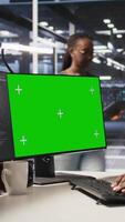 Vertical Data center programmer working on green screen desktop PC, updating storage infrastructure. IT specialist using mockup computer in server hub workspace filled with networking tech, camera A video