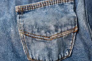 Close-up view of textured denim fabric showcasing intricate pocket details in a vibrant blue hue photo