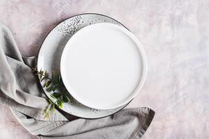 Pair of empty ceramic plates with napkin on gray background top view photo