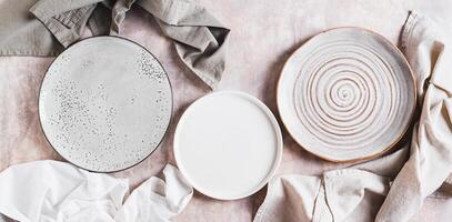 Three empty ceramic plates and napkins on light background top view web banner photo
