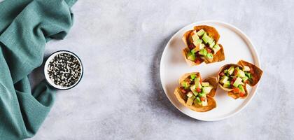 Mini baked pita cups with guacamole on a plate on a table top view web banner photo