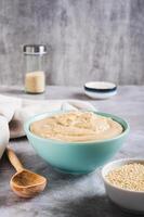 Sesame tahini in a bowl and sesame seeds in a bowl on the table vertical view photo