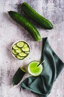 A glass of fresh cucumber juice and cucumbers on the table top and vertical view photo