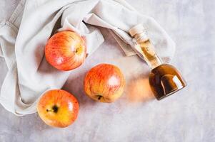 Apple cider vinegar in a bottle and fresh apples on the table top view photo