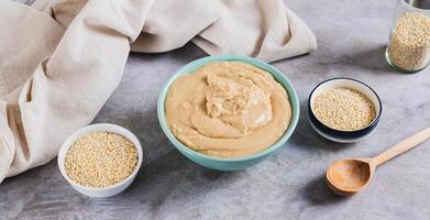 Sesame tahini in a bowl and sesame seeds in a bowl on the table web banner photo