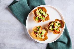 Close up of appetizing cups of guacamole in pita bread on a plate on the table top view photo