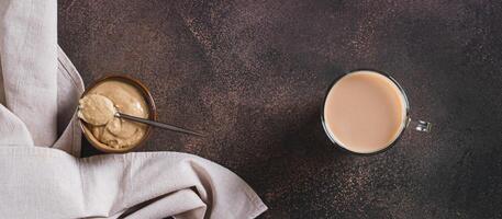 Coffee with sesame paste tahini in a cup on the table top view web banner photo