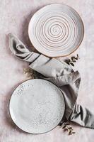 Pair of empty ceramic plates with napkin on gray background top and vertical view photo