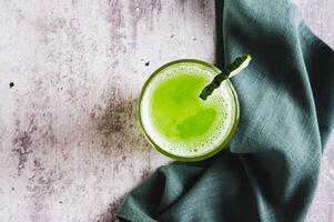 Close up of fresh cucumber juice in a glass and cucumber piece on the table top view photo