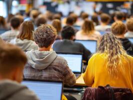 Students focused on laptops in a crowded classroom setting. photo