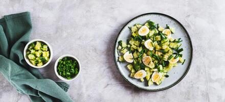 Appetizing mix of cucumbers, eggs and chives on a plate on the table top view web banner photo