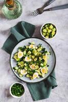 Appetizing mix of cucumbers, eggs and chives on a plate on the table top and vertical view photo