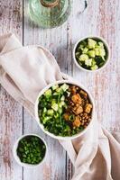 A bowl of buckwheat, meat, cucumber and green onions on the table top and vertical view photo