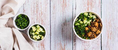 A bowl of buckwheat, meat, cucumber and green onions on the table top view web banner photo
