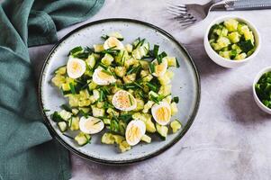 Appetizing mix of cucumbers, eggs and chives on a plate on the table photo