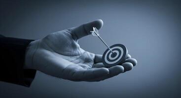 Hand Holding Target with Arrow Hitting Bullseye photo