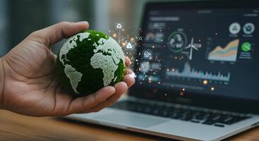 Earth Globe Held in Hand with Laptop Showing Environmental Data photo