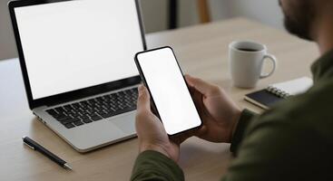 Person Holding Smartphone with Laptop and Mug photo