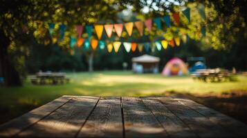 Rustic wooden picnic table in foreground with vibrant outdoor festive scene blurred in the background. Outdoor celebration concept photo