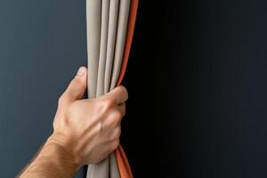 Hand pulls aside two-toned curtain against dark background, suggesting a reveal or transition in dramatic setting. Concept of anticipation photo