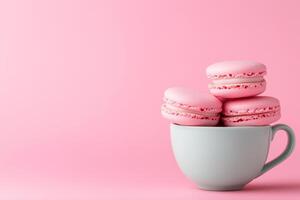 Pink macarons in teacup set against soft pink background, creating charming and inviting dessert presentation. Food concept photo