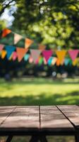 Rustic wooden table in foreground with colorful bunting blurred in background of sunny park. Summer celebration concept photo