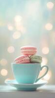 Pastel pink and green macarons in light blue teacup on saucer, against soft dreamy bokeh background, creating delightful dessert scene. Food concept photo