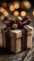 Holiday gift box decorated with ribbon and ornaments resting on wooden table with soft bokeh background photo