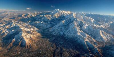 Mountain range covered in snow with a clear sky above a town during daylight photo