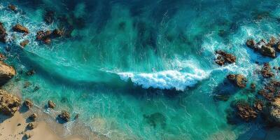 Coastal waves crash against rocky shoreline in a serene beach setting during daylight hours photo