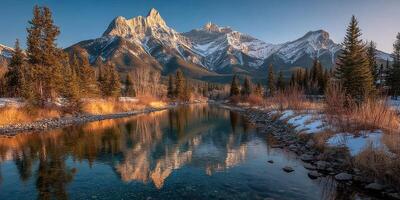 Majestic mountain range reflects in a tranquil river at dusk near a serene forest in wintertime photo