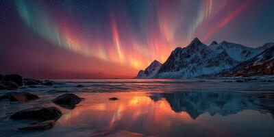 Majestic northern lights illuminate snowy mountains and a tranquil beach at dusk photo